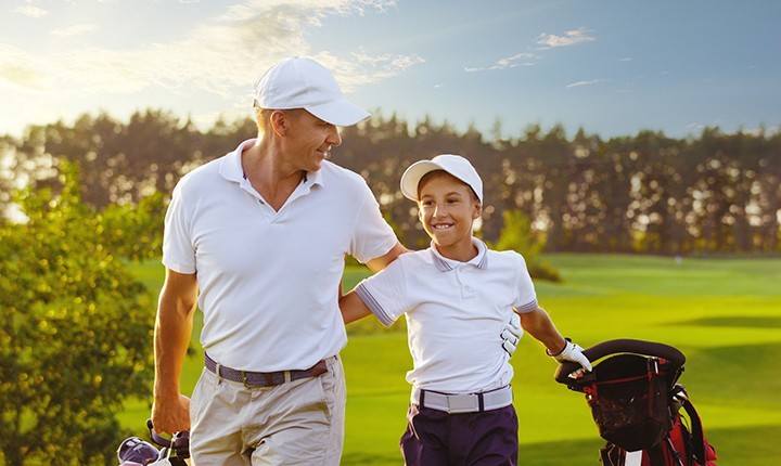 Father and son walking down golf course fairway
