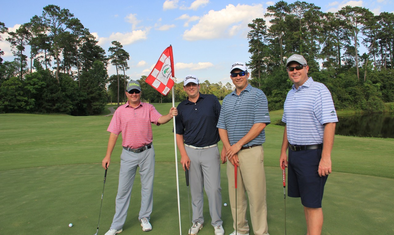 Foursome of golfers standing on a golf green