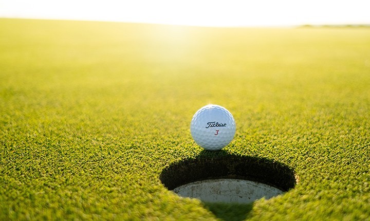 titleist golf ball on edge of golf cup